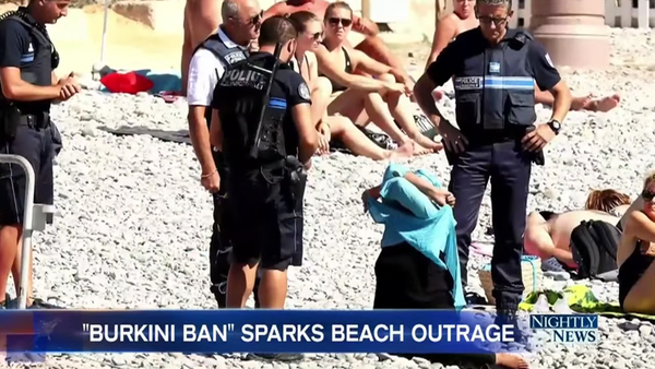 Fire politifolk i Nice, Frankrig, fotograferet, mens de tvang en kvinde til at fjerne dele af sin klædedragt, fordi hendes påklædning overtræder byens "burkiniforbud," den 23. august. De gav hende også en bøde for forseelsen. (Foto: NBC News video screenshot)